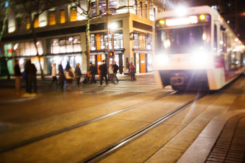 Portland, Oregon, USA - December 3, 2011: The Trimet MAX light rail runs through downtown Portland at night while pedestrians cross the street.