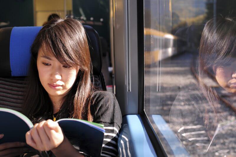 A female passenger is reading book on train