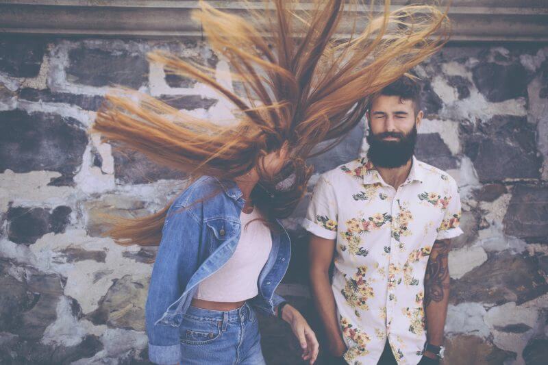 Retro style image hipster guy standing next to a hipster girl flinging her red hair wildly