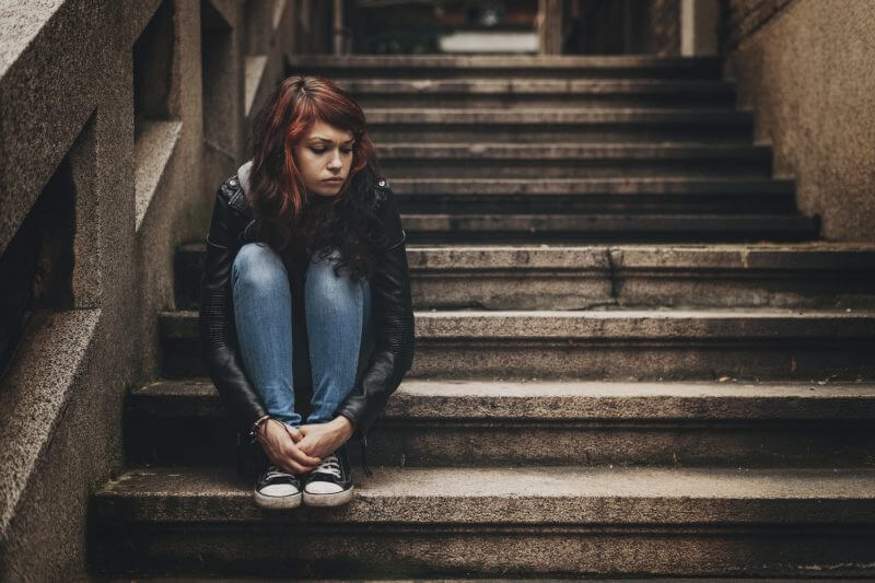 Lonely teenager sitting on stairs with copy space