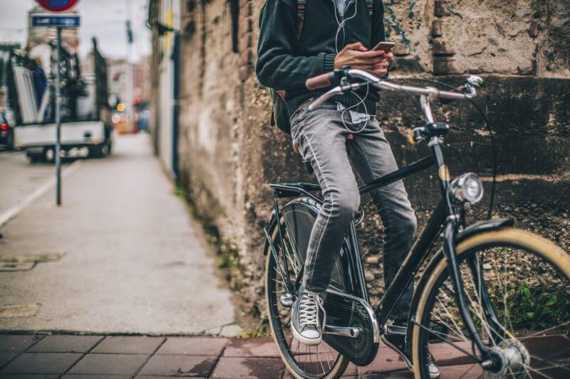 Young man enjoys bicycle ride in the city while using his mobile phone and surfing the net