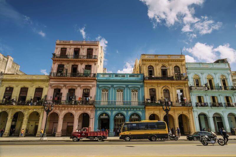 Havana, Cuba - November 6, 2015: Old apartment buildings in Old Havana, Cuba. Colourful facades of buildings facing Capitolio on Paseo Marti Boulevard. Rows of balconies with fresh laundry drying in the hot Caribbean Sun. Tenants outdoors, doing chores outside.Typical scene all around old Havana, where ever you see old buildings with people still living inside. Traffic and people on the street. Variety of colours and styles. Beauty of old architecture neglected over many years with out upkeep.