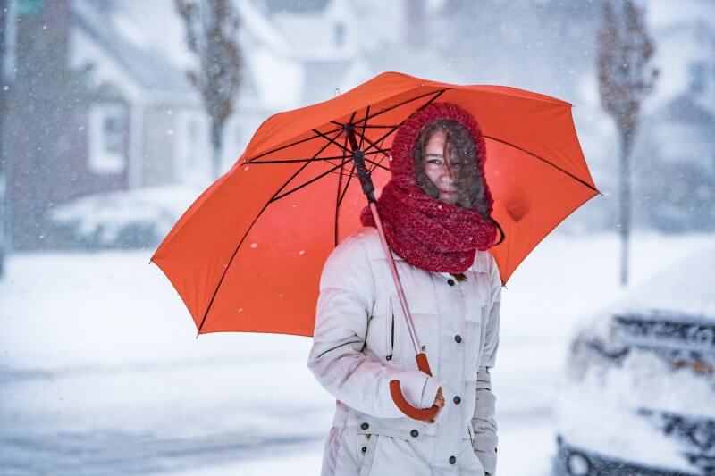 Teenager girl with umbrella under snowfall at the street in Queens Village, New York City, NY, during the snowstorm Jonas