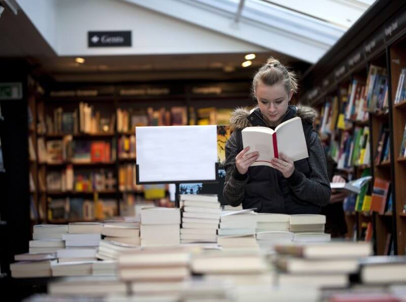 Young teenage girl engrossed in a book in a bookstore