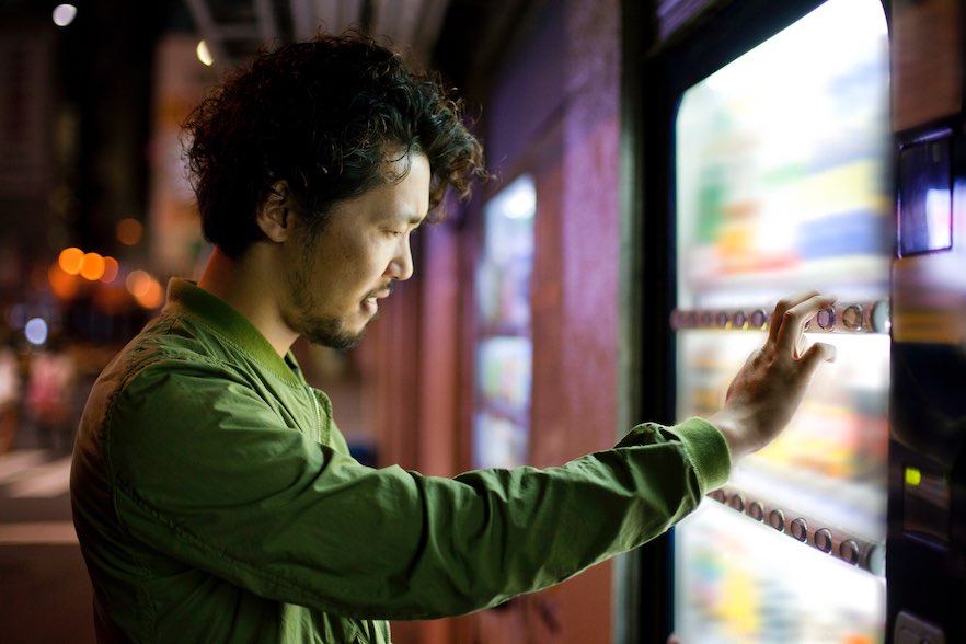 Young Japanese Man Using Vending Mashine in Tokyo.